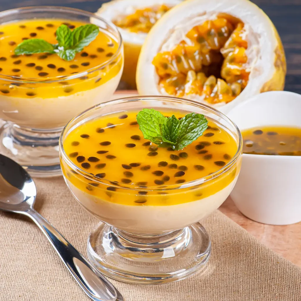 mousse de maracujá em taça transparente com sementes de maracujá e uma colher do lado.