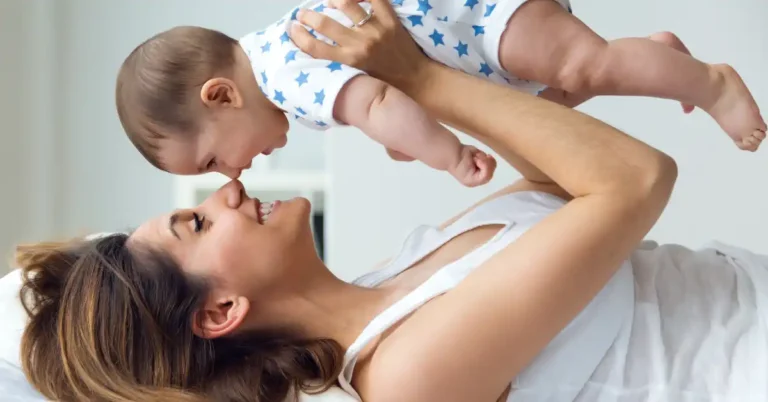 Pessoa segurando bebê com body branco de estrelas azuis; cena carinhosa que inspira nomes com significado de luz e conexão.