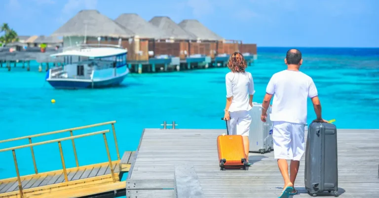 casal chegando a hotéis temáticos sobre o mar em resort tropical com malas de viagem