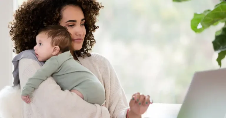 Mãe empreendedora com filho no colo enquanto trabalha no laptop, representando a rotina de mães empreendedoras com filhos.
