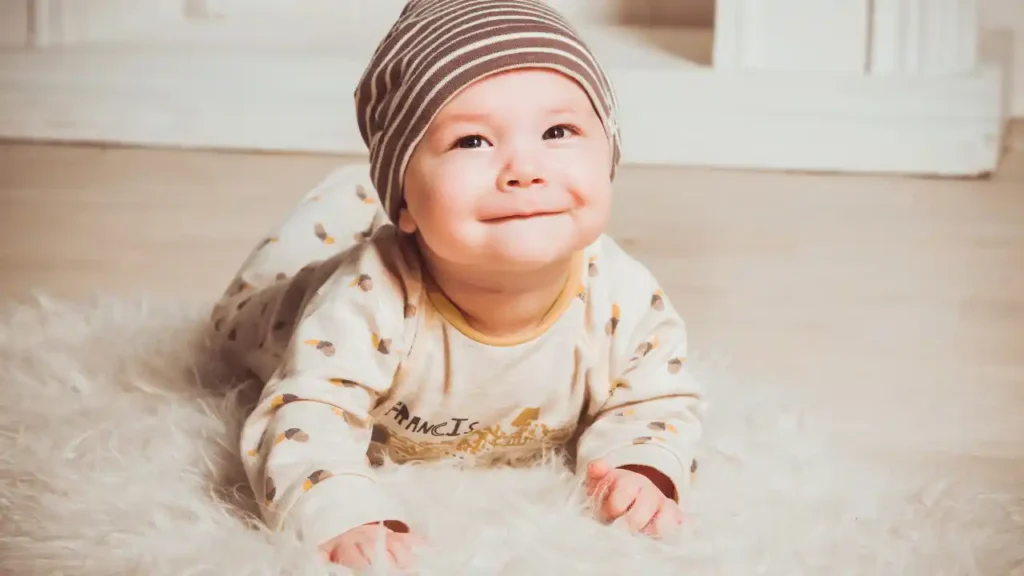 Bebê deitado em tapete branco com roupa clara estampada e touca listrada; cena tranquila que inspira nomes com significado de luz e acolhimento.