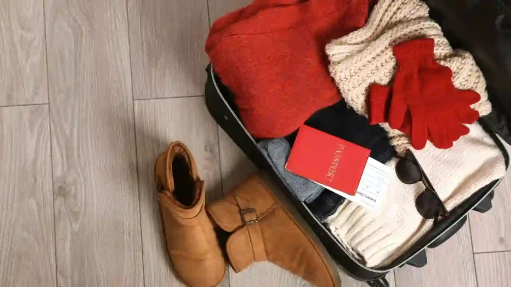 Mala aberta com roupas de frio, acessórios e passaporte — exemplo prático de o que levar na mala para viagem de inverno.