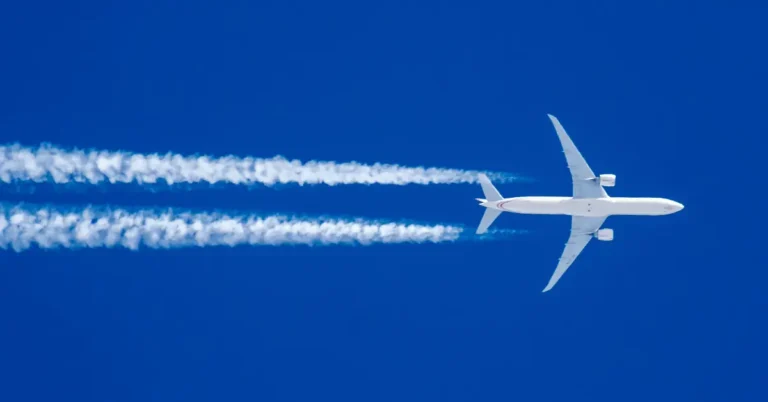Avião comercial em altitude de cruzeiro com rastros de condensação, simbolizando momento ideal para refeição antecipada no trajeto aéreo.