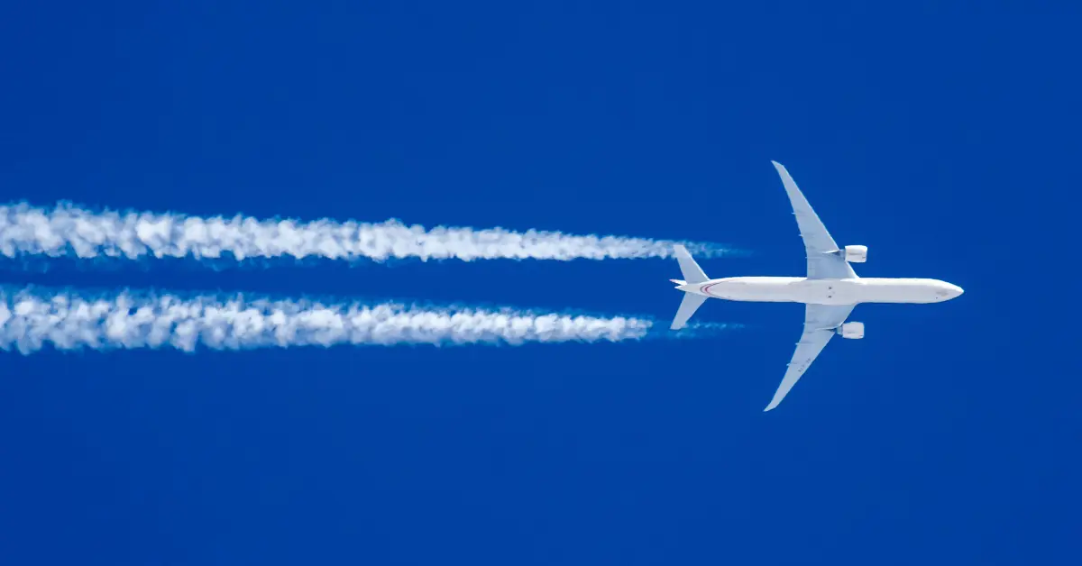 Avião comercial em altitude de cruzeiro com rastros de condensação, simbolizando momento ideal para refeição antecipada no trajeto aéreo.