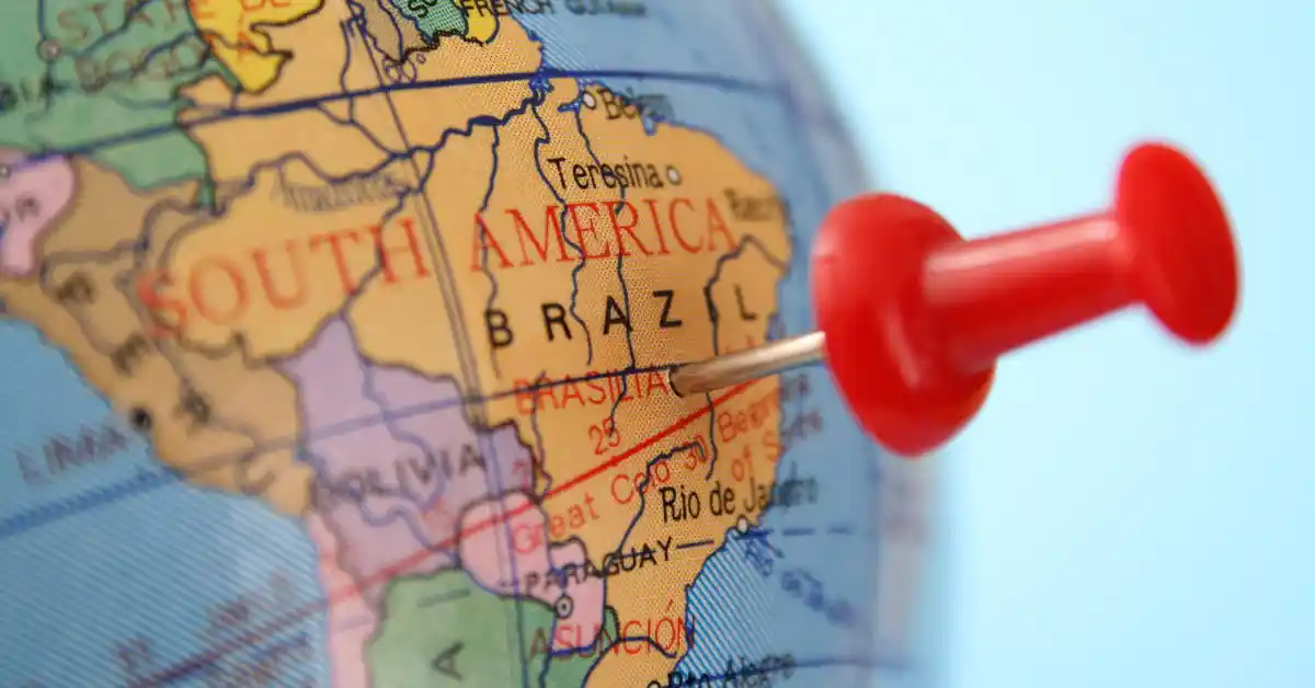 Globo terrestre com alfinete vermelho marcando Brasília, destacando o turismo internacional no Brasil e seu papel como destino estratégico na América do Sul.