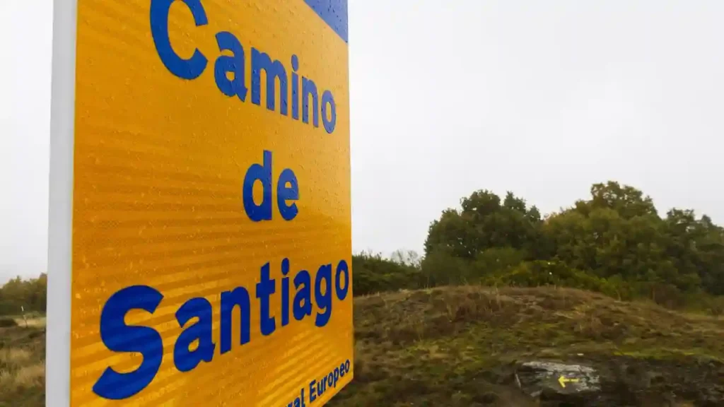 Viagens que atravessam fronteiras a pé – Placa do Caminho de Santiago com fundo amarelo e letras azuis, destacando seu reconhecimento como Itinerário Cultural Europeu.