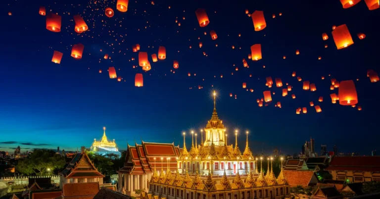 Templo iluminado em uma cidade asiática durante festival de luzes com lanternas flutuantes no céu noturno