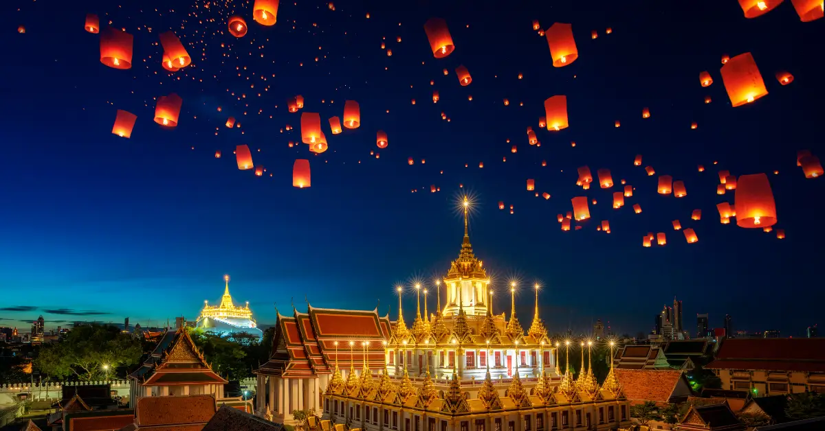 Templo iluminado em uma cidade asiática durante festival de luzes com lanternas flutuantes no céu noturno