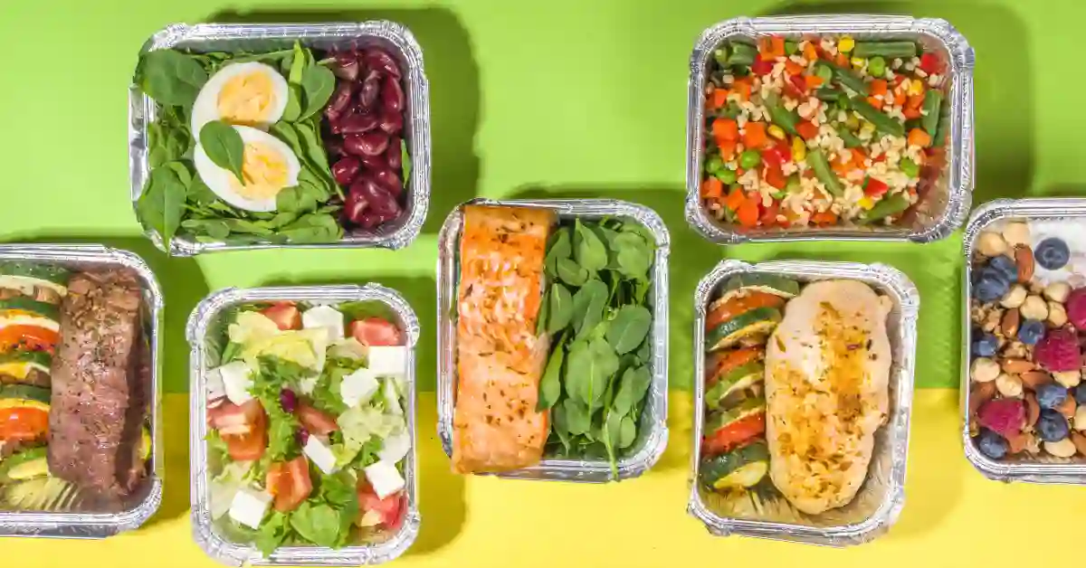 Diversas marmitas baratas com opções saudáveis de saladas, carnes e legumes organizadas sobre fundo verde e amarelo.