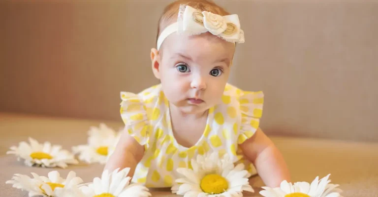 Bebê com vestido amarelo de bolinhas e faixa com flor entre margaridas brancas; imagem doce que inspira nomes naturais raros com toque floral e sensibilidade.