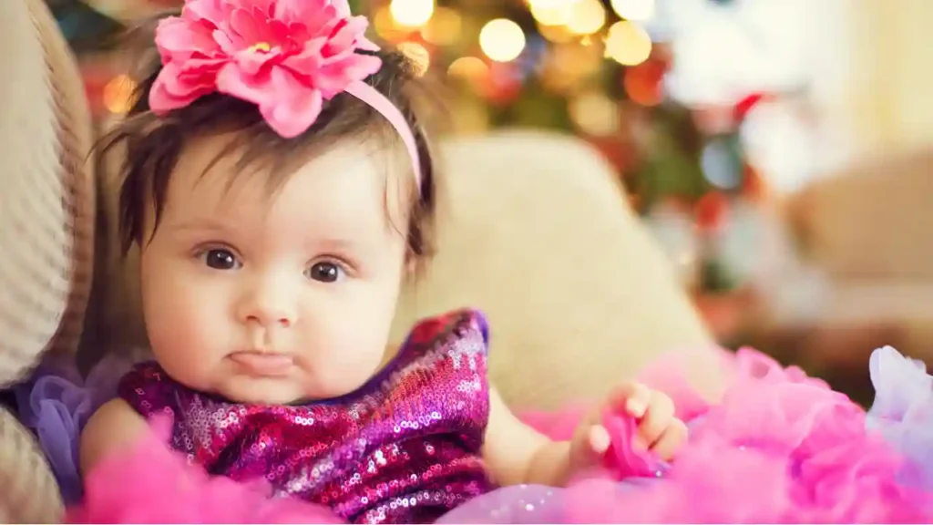 Criança com tiara de flor rosa e vestido brilhante em meio a tule colorido; imagem festiva que remete a nomes naturais raros com aura mágica e delicada.
