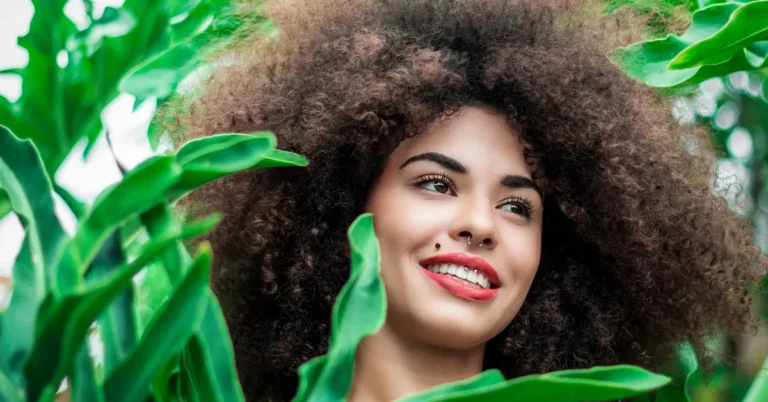 Tendências de decoração 2025 com elemento natural: cabelo volumoso emoldurado por folhas verdes vibrantes.