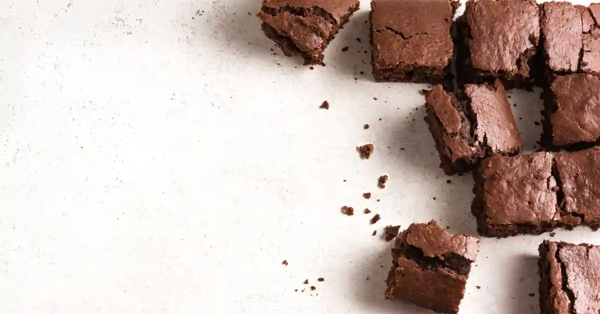 Brownies fit e saudáveis dispostos sobre uma superfície clara, com textura densa e aparência caseira.