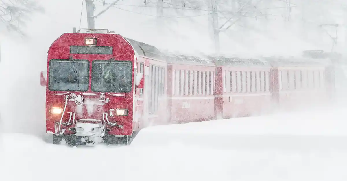 Trem vermelho atravessando paisagem nevada intensa, ilustrando os desafios climáticos e o que levar na mala para o Transiberiano.