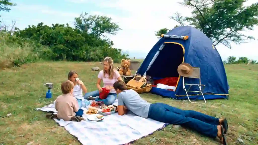 Família fazendo piquenique ao lado de barraca de camping, ilustrando momentos ao ar livre e ideias sobre o que levar na mala para vinhedo.