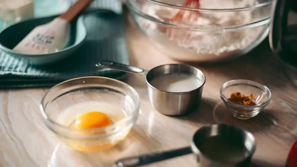 Ingredientes para preparo rápido de receitas de 10 minutos: ovo, leite, raspas de laranja e farinha sendo misturada com um batedor.