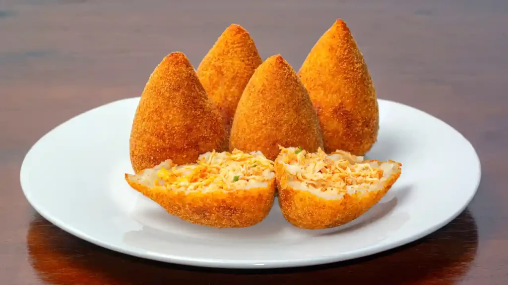 Coxinhas brasileiras servidas em prato branco, com recheio de frango visível — versão de salgadinho na air fryer.