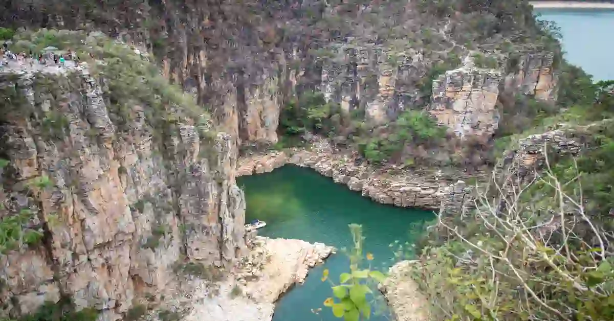Cânion com paredões rochosos e vegetação esparsa ao redor de um lago verde-esmeralda, ilustrando destinos brasileiros que unem natureza e bem-estar.