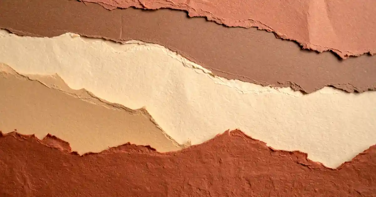 Camadas de papel rasgado em tons terrosos, sugerindo texturas naturais e ideias para pintar muros agora com inspiração artística.