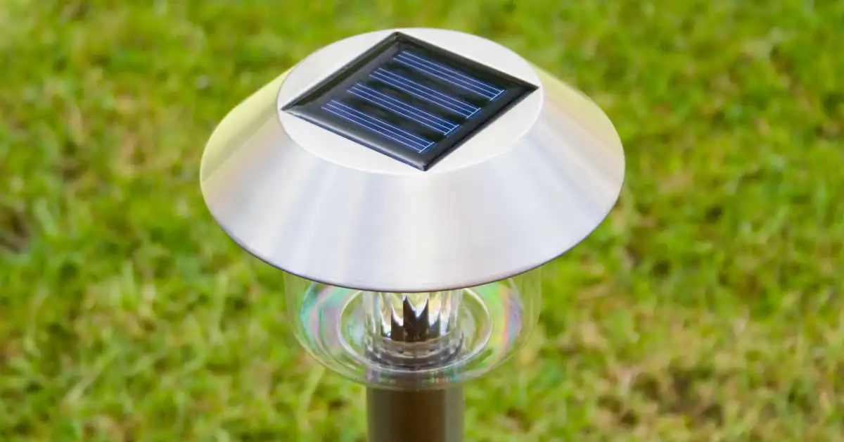 Luminária solar sobre a grama, revelando o segredo da iluminação no quintal com energia sustentável.