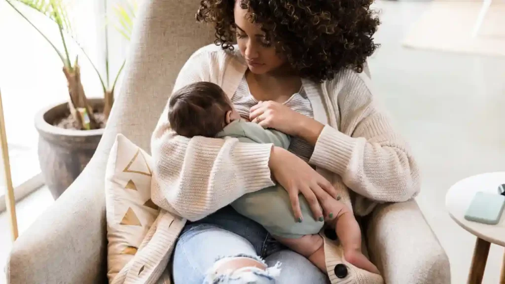 Mãe sentada em poltrona aconchegante, segurando seu bebê com carinho — uma imagem que expressa como a verdade sobre ser mãe muda tudoa.