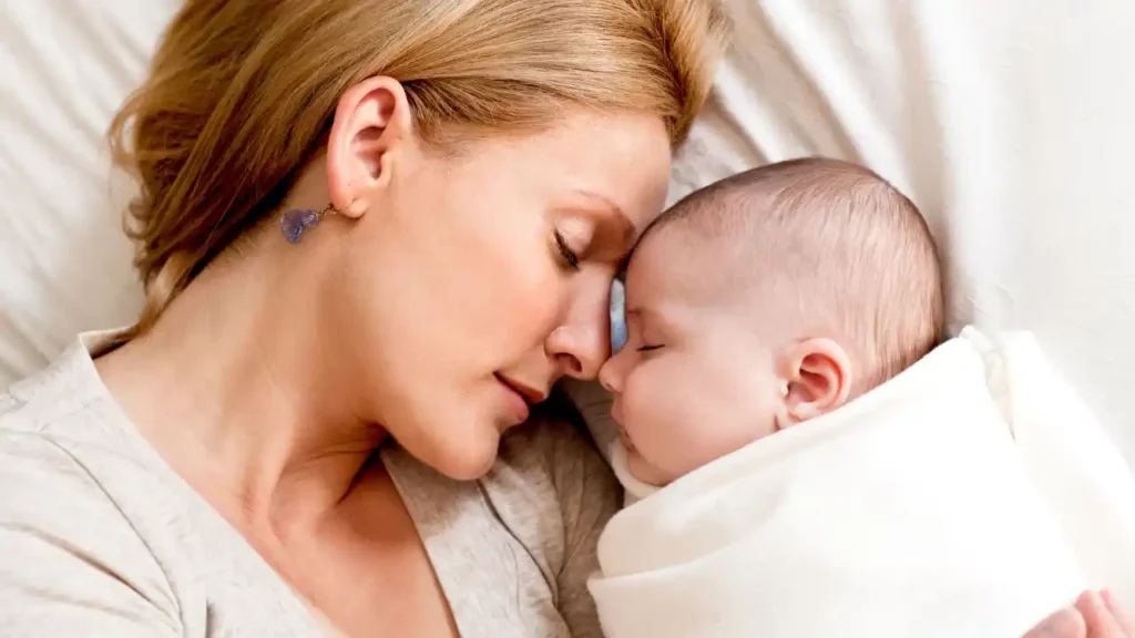 Mãe descansando com seu bebê recém-nascido, simbolizando o vínculo emocional vivido no início da maternidade.